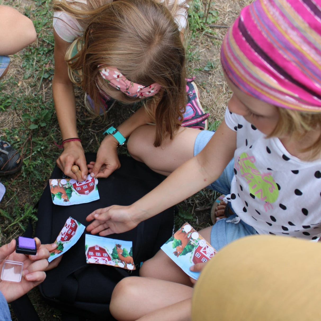 Kinder sitzen bei einem Kindergeburtstag im Kreis um den Eventrucksack und stempeln ihre Pferdepässe ab.